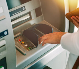 Woman entering her pin number into an ATM machine